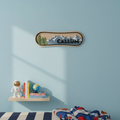 Decorative wall patch shaped like a snowboard with mountains and trees on a light blue wall above a shelf with books and a globe.